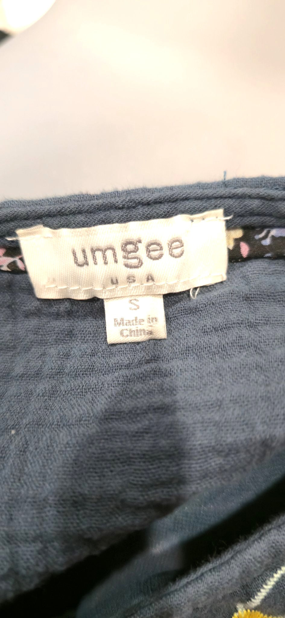 Umgee USA brand tag and size S label sewn onto the navy embroidered dress